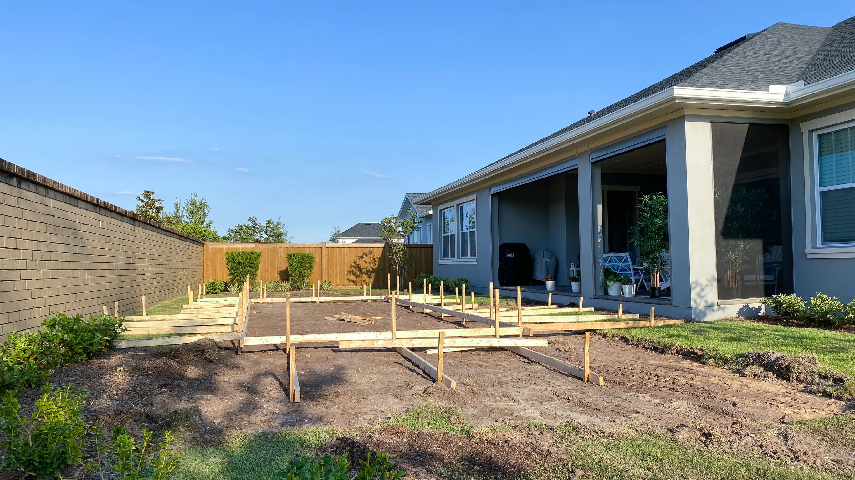 Before image of an attached ADU project in Los Angeles showing backyard construction preparation with foundation framing and open ground beside the main house