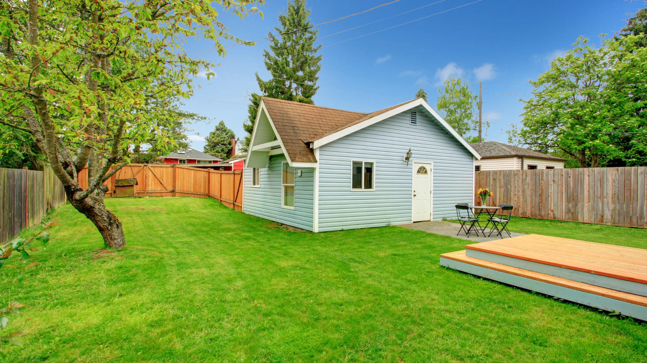 After image of a backyard guest house project in Los Angeles showing a completed cottage style guest house with light siding, fenced yard, green lawn, and outdoor deck